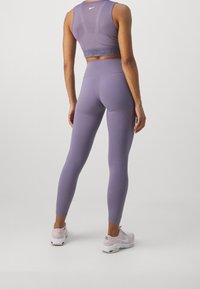 Top corto sportivo viola con una fascia testurizzata e leggings viola abbinati, caratterizzati da un design elegante e aderente e una lunghezza fino alla caviglia.