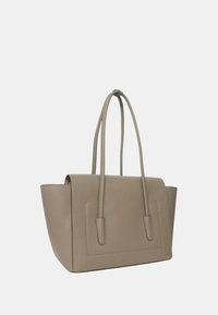 Sac fourre-tout en cuir beige avec deux poignées et un design structuré. Présente une texture lisse et des accents de couture discrets sur les côtés.
