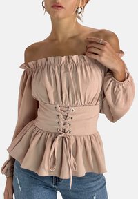 Blusa rosa chiaro senza spalle con tessuto arricciato, vita con lacci e orlo arruffato. Maniche lunghe a sbuffo con polsini elasticizzati.