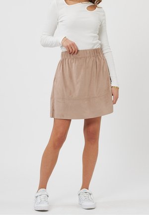 Jupe beige clair avec ceinture élastique, fabriquée en matériau doux semblable à du daim, présente une texture lisse et une forme légèrement évasée.