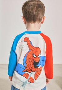 Rood en blauwe raglan-sleeve t-shirt met een grote afbeelding van Spider-Man in een actiepose op de achterkant. Gemaakt van katoen.