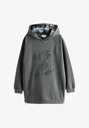 Tummanharmaa huppari, jossa on kukkakuosiset huppukangaspinnat, brodeerattu "by Ted Baker" -teksti ja kultaiset sivuvetoketjut hemissä.