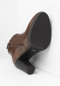 Brown leather boot with a high heel. Features a side zipper and textured rubber sole. The color is rich and the shape is streamlined.