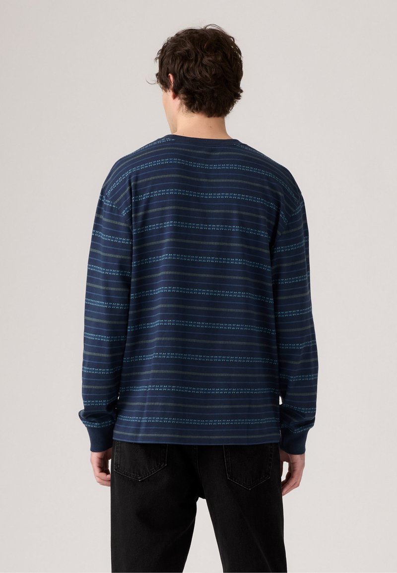 Maglietta a maniche lunghe blu navy con righe orizzontali azzurro chiaro, dotata di scollatura a girocollo e vestibilità rilassata. Realizzata in un tessuto morbido e testurizzato.