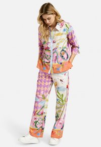 Colorful patterned shirt and pants set with a mix of pink, purple, and orange hues. Features botanical and animal motifs, and a relaxed fit.