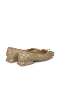 Ballerine beige con un design perforato, dettagli in metallo quadrato e un piccolo tacco a blocco. Il fiocco sul davanti aggiunge una decorazione delicata.