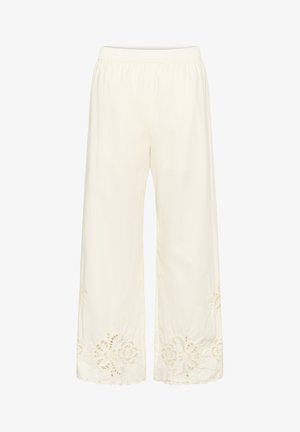 Pantaloni largi crem cu talie elastică și modele decorative din dantelă decupată lângă tivul ondulat.