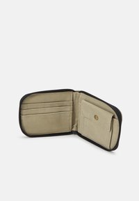 Portafoglio in tessuto beige con chiusura a zip, dotato di tre scomparti per carte e una tasca con bottone a pressione. L'interno ha una superficie liscia.