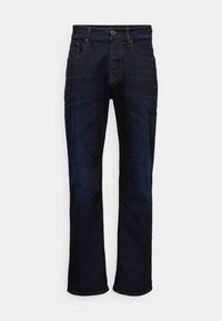 Mørkeblå denim jeans med lige ben, fem lommer og kontraststing. Materialet har en glat, vævet tekstur.
