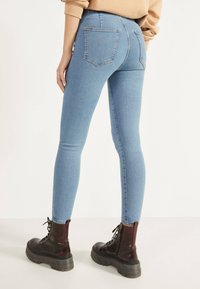 Ljust blå skinny jeans med bakfickor, hög midja och texturerad denim, tillsammans med svarta kängor med tjocka sulor.