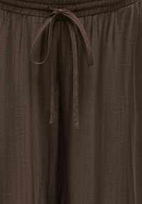 Pruunid kerged kangast püksid elastse vöökoha ja keskel ees seotud nööriga.