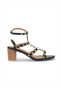 Zwarte leren hoge sandaal met gestoken accenten, met een verstelbaar enkelbandje en een stevige houten hak met een gestructureerd oppervlak.