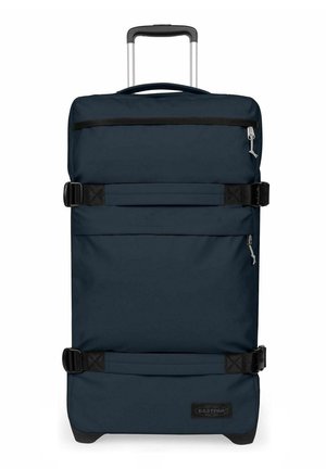 Valise bleu foncé à coque souple avec roulettes, poignée télescopique, deux poches avant zippées et deux sangles noires réglables à l'avant.