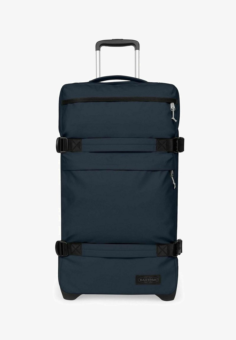 Valise bleu foncé à coque souple avec roulettes, poignée télescopique, deux poches avant zippées et deux sangles noires réglables à l'avant.