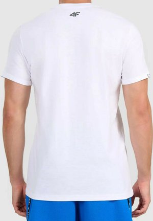 Achteraanzicht van een persoon die een effen wit T-shirt met korte mouwen draagt met klein zwart "4F"-logo op de bovenrug, blauwe shorts, staand tegen een witte achtergrond.