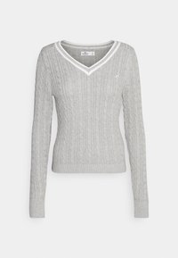 Ljusgrå kabelstickad tröja med långa ärmar, V-ringning och vit kant vid kragen. Har en figurnära design och ribbad krage.