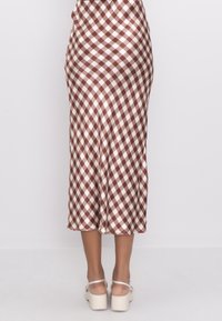 Ruskea ja kermaan värinen ruudullinen midi-hame, joka on valmistettu sileästä kankaasta. Hameessa on istuva vyötärö ja helma levenee hieman alaspäin.