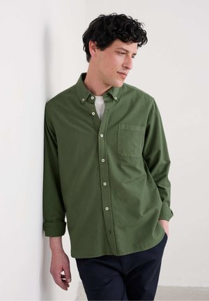 Groene button-down shirt van een gestructureerde stof, met een borstzak en een relaxte pasvorm. Gecombineerd met donkere broek.