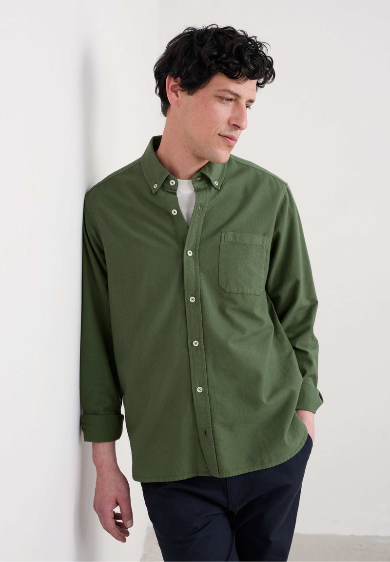 Groene button-down shirt van een gestructureerde stof, met een borstzak en een relaxte pasvorm. Gecombineerd met donkere broek.
