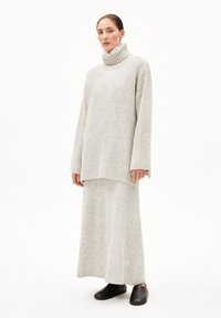 Hellgrauer gerippter Strickrollkragenpullover mit weiten Ärmeln, kombiniert mit einem passenden knielangen Rock und schwarzen Slippern.