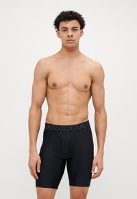 Schwarze, enganliegende Boxer-Briefs mit einem elastischen Bund mit Logo, gefertigt aus einem glatten, dehnbaren Stoff, mit einem konturierten Beutel zur Unterstützung.