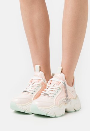 Pastelroze sneakers met een glanzende afwerking, witte veters en een mintgroene zool; heeft een decoratieve zilveren hanger aan de zijkant.