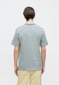 Ριγέ μπλούζα σε ανοιχτό τιρκουάζ και λευκό, κατασκευασμένη από βαμβάκι. Διαθέτει κοντά μανίκια, στρογγυλή λαιμόκοψη και άνετη εφαρμογή.