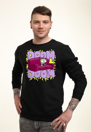 Man draagt een zwarte trui met een tekenfilm-achtige alien, zittend op een paarse bank en de tekst "DOOM DOOM" in grote paarse letters.