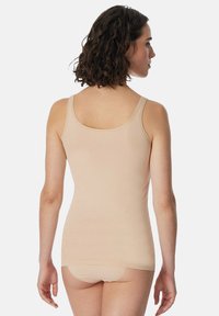 Top senza maniche beige realizzato in tessuto morbido, con scollatura rotonda, spalline sottili e design aderente. Mostrato da dietro con slip coordinati.