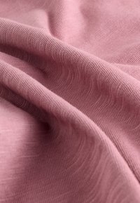 Tessuto rosa tenue con motivo testurizzato, caratterizzato da onde delicate e una trama fine e liscia, che mostra sottili variazioni di tonalità.