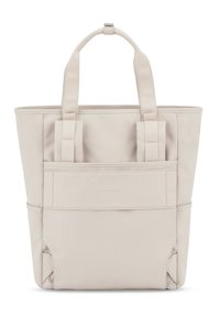 Beige canvas tote-väska med dubbla handtag, med en framficka och sidodetaljer. Slät textur, strukturerad design.