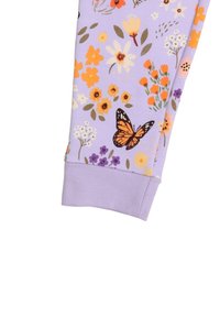 Lila Stoff mit einem floralem Muster aus orangefarbigen, gelben und lila Blumen sowie einem Schmetterling. Abgeschlossen mit einem einfarbigen lilafarbenen Bündchen.
