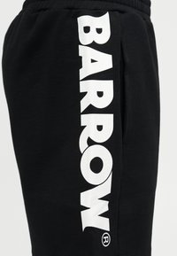 Μαύροι φόρμες με μεγάλο λευκό κάθετο κείμενο "BARROW" τυπωμένο στην πλευρά και ελαστική μέση ορατή στο πάνω μέρος.
