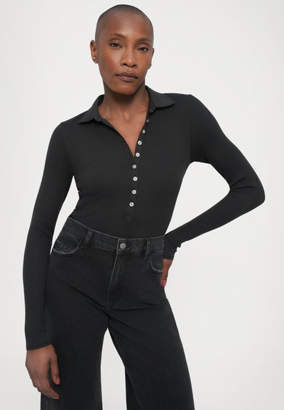 Black ribbed long-sleeve polo bodysuit with a buttoned placket. Paired with high-waisted black wide-leg jeans. The fabric is smooth and fitted.