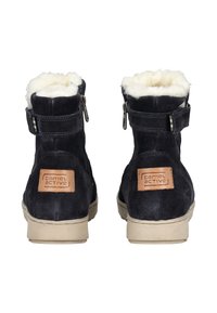 Black suede ankle boots with white faux fur lining, side zippers, and tan leather accents featuring logo on the back. Flat rubber soles.