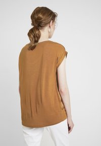 Camiseta de manga corta marrón con un ajuste relajado, hecha de una tela suave, que presenta un escote redondo y una textura lisa.