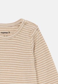 Top de manga larga beige con un escote redondeado, que presenta finas rayas verticales en beige claro y oscuro, fabricado en una textura de tela acanalada.