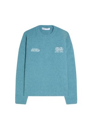 Kék kerek nyakú pulóver fehér felirattal: "SUNDAY’S AFFAIR" és az alábbi címmel a mellkasán: "64 Yardfield Avenue, New York Lifestyle Studio".