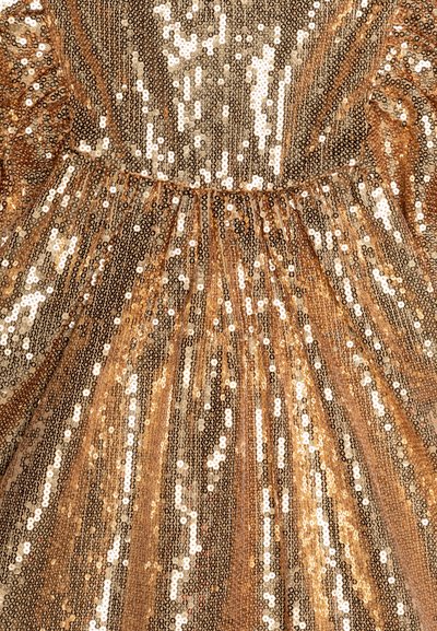 Tessuto in sequins dorati con una texture scintillante, caratterizzato da sequins di diverse dimensioni che creano un motivo verticale e bordi arricciati.
