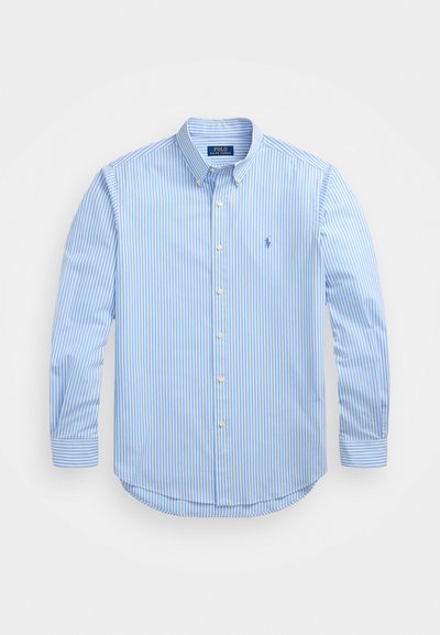 Camisa riscada azul e branca, feita de um tecido leve, com gola de botões, mangas longas e pequeno logótipo bordado no peito.