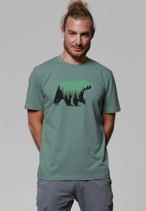 Mint green t-shirt with a graphic of a bear and trees in black and green tones. Short sleeves and a crew neckline. Soft fabric texture.