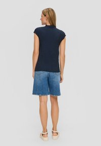 Marineblauw textuur T-shirt met korte mouwen en een rimpelachtige halslijn, gecombineerd met denim shorts met een rafelrand, met een ontspannen pasvorm en een lichte wassing.