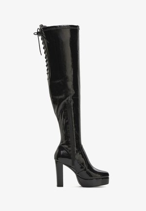 Schwarzer Stiefel aus Lackleder, kniehoch, mit hohem Blockabsatz, seitlichem Reißverschluss, Plateau-Sohle und Schnürdetail am oberen Rücken.