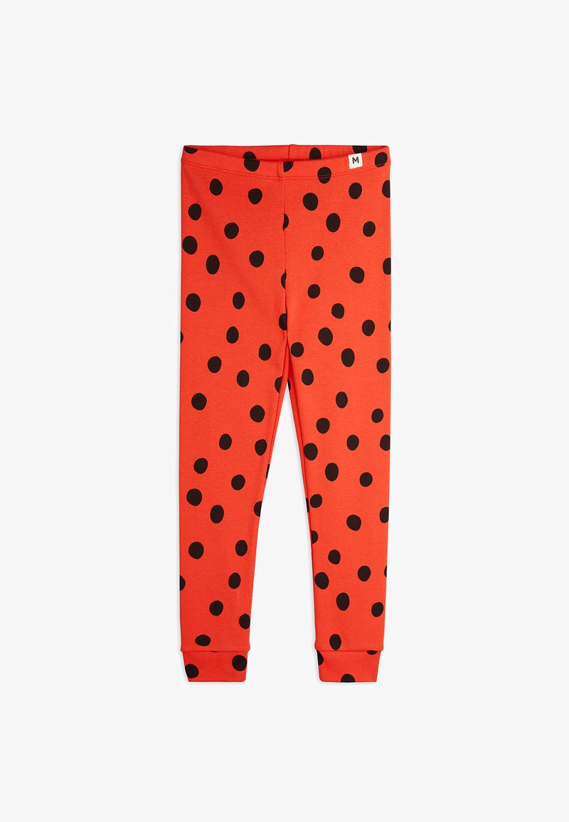 Red leggings made of soft fabric featuring a pattern of large black polka dots. Elastic waistband with a label at the top. Fitted shape.