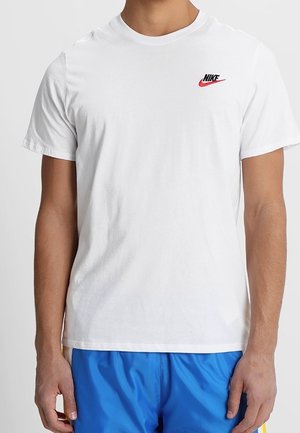 T-shirt en coton blanc présentant un logo Nike noir et rouge sur la poitrine gauche, col rond et manches courtes.