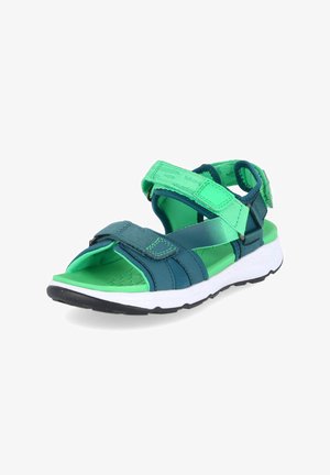 Sandalia deportiva con tiras ajustables en verde azulado y verde, plantilla acolchada verde y suela blanca con dibujo negro, mostrada en ángulo para ver el lateral y la parte superior.