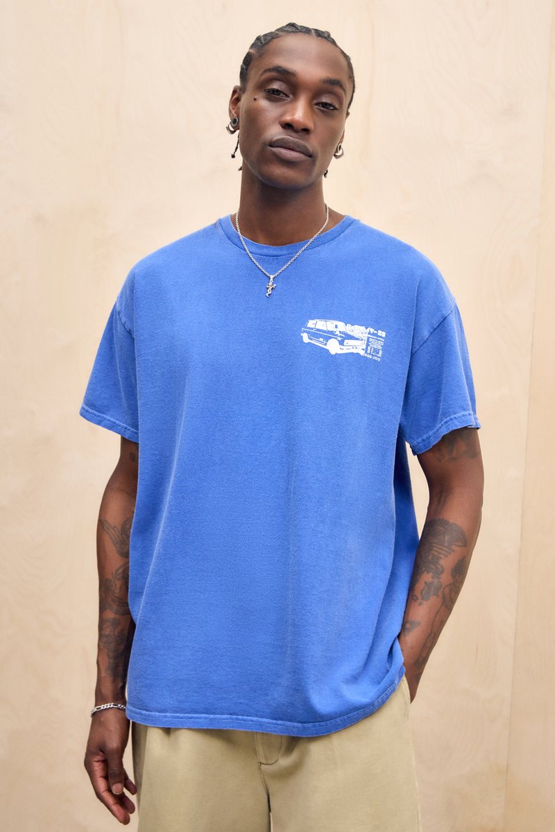 Sinine puuvillane T-särk lühikeste varrukatega, millel on valge graafiline kujundus vasakul rinnal. Lahtine lõige, ümmargune kaelus ja pehme tekstuur.