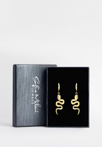 Orecchini a forma di serpente in oro con dettagli intricati, posizionati all'interno di una scatola di velluto blu scuro con un logo argentato.