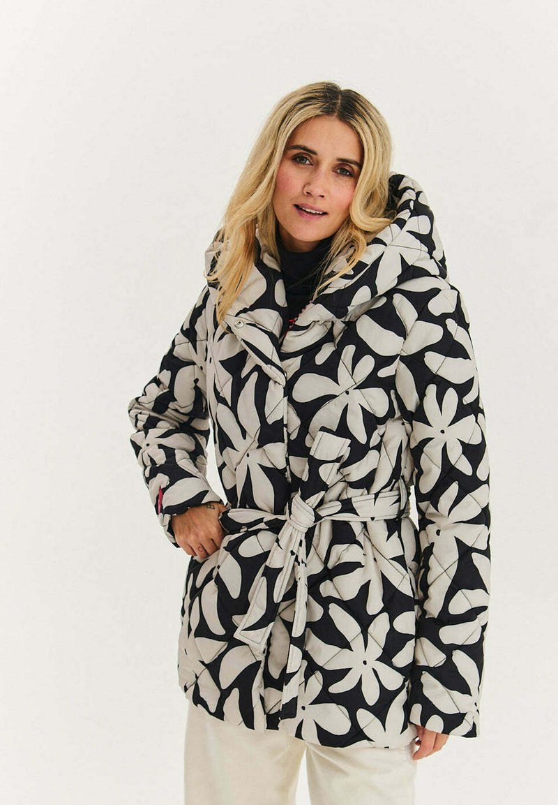 Černobílý prošívaný kabát s květinovým vzorem, s kapucí, páskem v pase a prošívanou strukturou; má široký límec a boční kapsy.