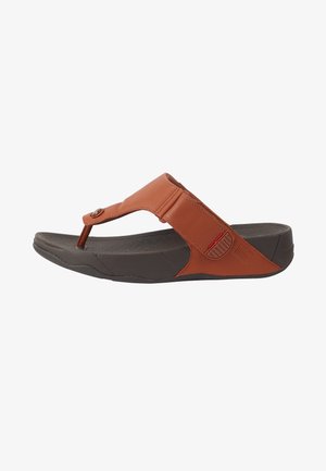 Bruine leren slippers met een teenbandontwerp, verstelbare band en een gestructureerde donkergrijze zool met een lichte kromming.